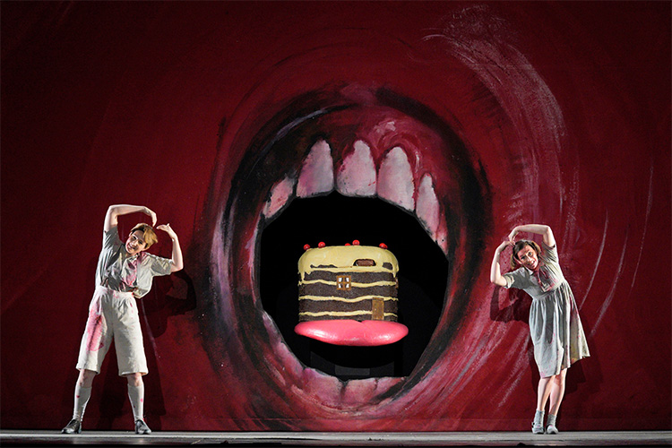 Hansel and Gretel dancing around a giant mouth background.